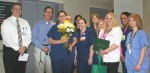 From left, Eric Wallis, CNO, and Dr. Cregg Ashcraft, hospitalist, surprise Heather Hill (center with flowers) with the presentation of The DAISY Award. Heather is surrounded by her co-workers, from left, Sarah Nagy, Emily Wagner, Angela Collins, Anita Ketcham, Sarah Nicholson, Michelle Sharp, Ashley Loehr, and Tammy Pennington.